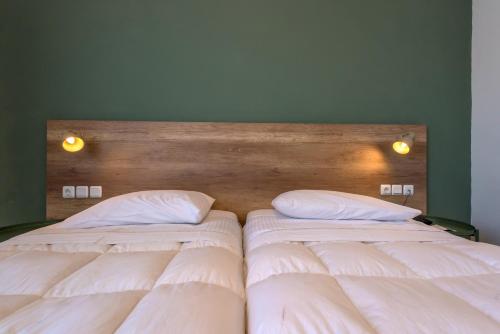 two beds in a bedroom with white sheets and pillows at Alexios Hotel in Ioannina