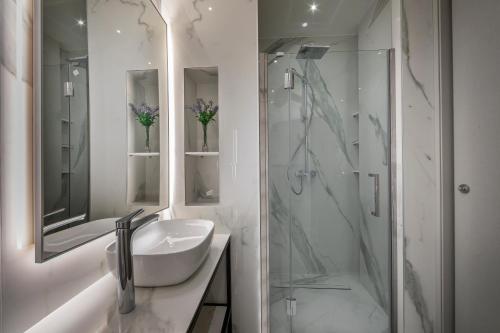 uma casa de banho branca com um lavatório e um chuveiro em Maralia Hotel em Nicósia