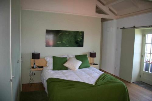 a bedroom with a large bed with green sheets at A Casa do Ouvidor in São Roque do Pico