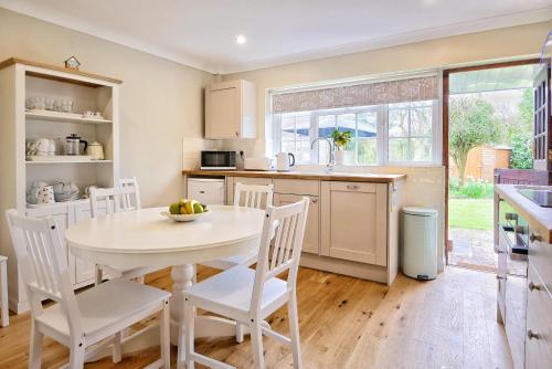 a kitchen with a white table and white chairs at 'BRAMLEY FALL COTTAGE' NEW AVAILABILITY - Attached Cottage,3 Bedrooms-1 on ground level, SLEEPS 6-2 Bathrooms, Wittering and Chichester easy drive, Child friendly,Small Breed Dog Friendly 2 max, Parking-EV Point in Chichester