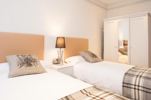 una camera con 2 letti e una lampada di Autèntic Arc de Triomf Apartment a Barcellona