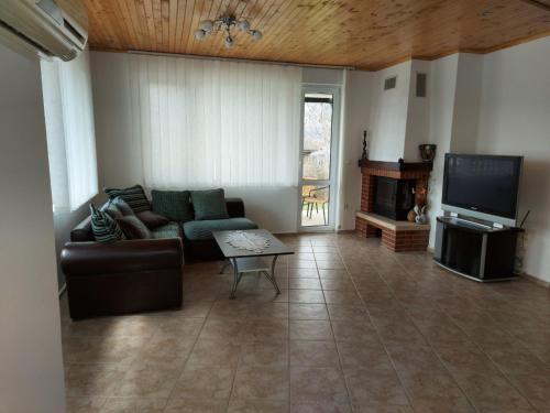 ein Wohnzimmer mit einem Sofa und einem TV in der Unterkunft Вила Текето in Obrochishte