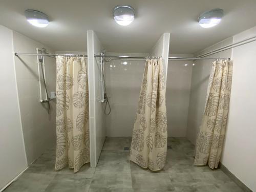 een inloopdouche met gordijnen en verlichting in de badkamer bij Хостел Декабрист in Tsjita