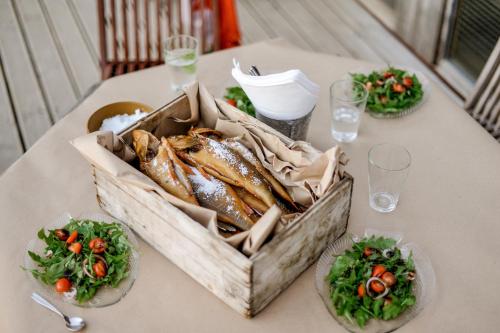 a basket of fish on a table with salad at Vēju Paradīze in Pāvilosta