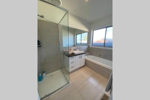 a bathroom with a shower and a tub and a sink at Sun-lovers Beach House - Walk to beach/shops! in Rosebud