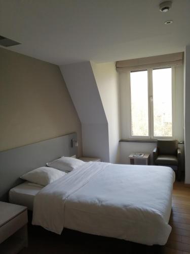 a bedroom with a large white bed and a chair at Het Rustpunt in Ghent