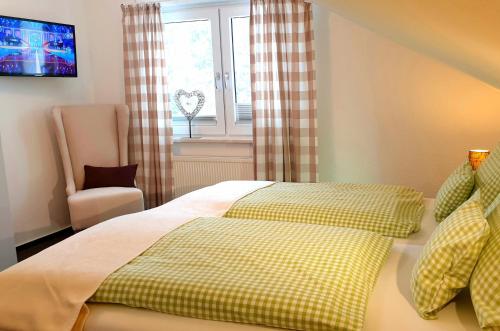 a bedroom with a bed with a chair and a window at Gästehaus Sonnenhügel in Möhnesee