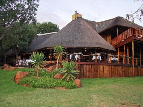 a large building with a thatched roof with chairs at Itaga Luxury Private Game Lodge in Bela-Bela