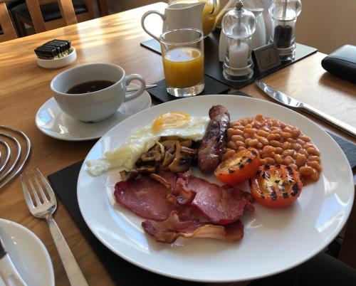 Un plato de desayuno con huevos, tocino, frijoles y una taza de café. en Beaumont House, en Great Yarmouth