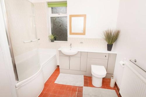 a white bathroom with a sink and a toilet at The Bungalow at Seaway's, Sleeps 11 + in Great Driffield