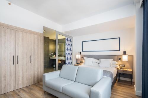a bedroom with a white bed and a couch at Hotel LIVVO Fataga in Las Palmas de Gran Canaria