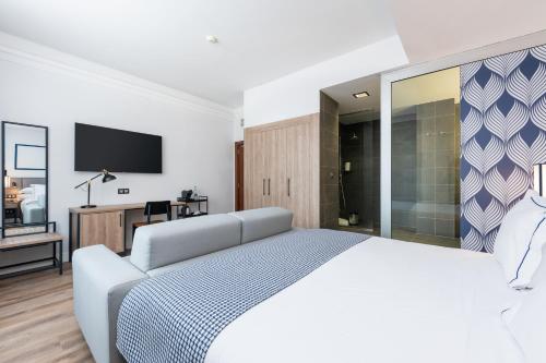 a white bedroom with a large bed and a tv at Hotel LIVVO Fataga in Las Palmas de Gran Canaria