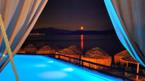 a swimming pool with a view of the ocean at night at Venus Beach Hotel in Nea Stira