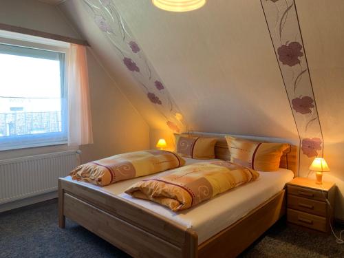 1 dormitorio con 2 camas y ventana en Pension am Kurgarten, en Bensersiel