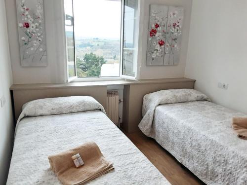 two beds in a room with two windows at Pensión Casa do Gallo Sarria in Sarria