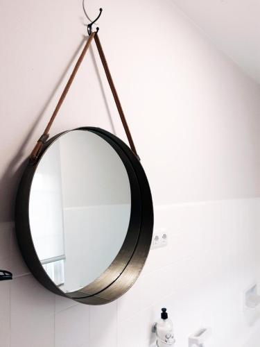 a mirror hanging on a wall in a bathroom at Pensión Casa do Gallo Sarria in Sarria