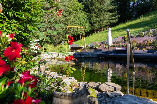 a garden with a pond with red flowers and a boat at Boutiquehotel Bergvilla in Dafins