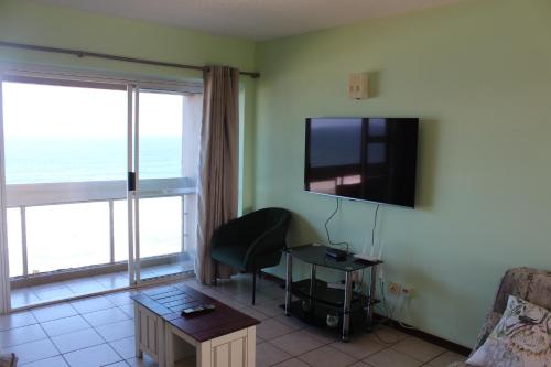 a living room with a couch and a tv on the wall at Stella Maris 144 in Amanzimtoti