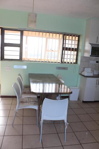 a dining room with a table and chairs in a kitchen at Stella Maris 144 in Amanzimtoti