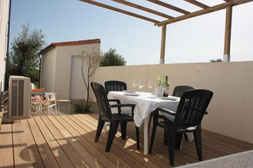 une table à manger et des chaises sur une terrasse en bois dans l'établissement Gîte du Couchant, à Sorède