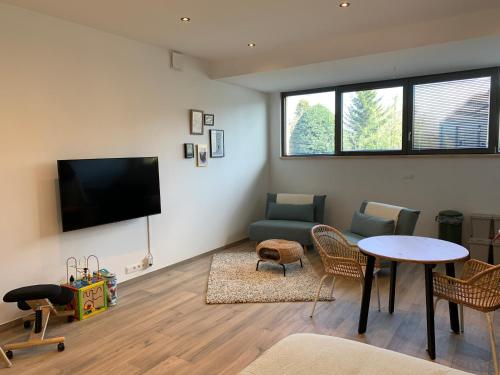 sala de estar con TV, mesa y sillas en Green studio-Situé à 15 min de Botrange, Parc Hautes Fa gnes et Francorchamps, en Heusy