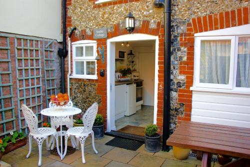 a patio with a table and chairs and a kitchen at Romantic Flint Cottage on the Suffolk Coast in Saxmundham