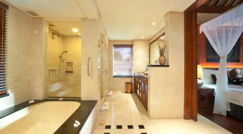 a large bathroom with a tub and a bedroom at Pool Villa Merumatta Senggigi in Senggigi