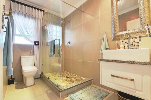 a bathroom with a shower and a toilet and a sink at Uvongo - Beach Paradise & Open Ocean View in Uvongo Beach