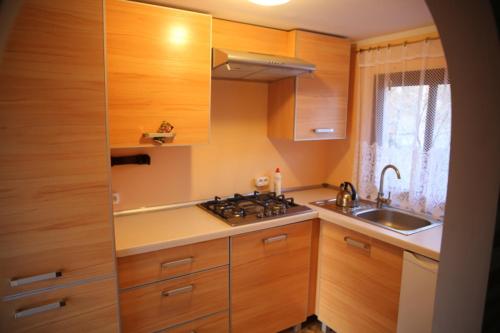 een keuken met houten kasten, een fornuis en een wastafel bij Domek letniskowy in Dybowo
