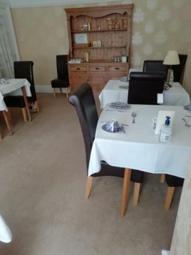 a dining room with white tables and black chairs at St Davids & Moorfield Hotels Chapel Street in Llandudno