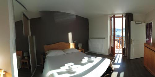 a bedroom with a bed and a door to a balcony at Hôtel du Soleil in Aillon-le-Jeune