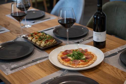 a table with a plate of pizza and wine glasses at Morum City Hotel Chania in Chania Town