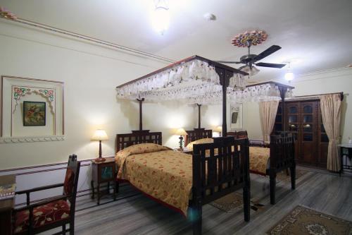 a bedroom with a canopy bed and two chairs at Jagat Palace in Pushkar