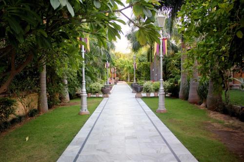 a walkway through a park with trees and poles at Jagat Palace in Pushkar