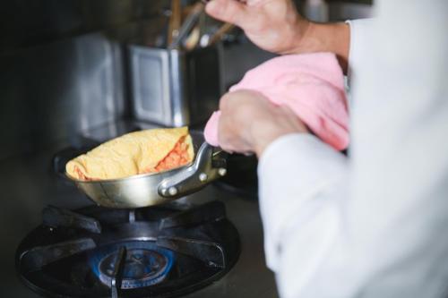 a person is cooking food on a stove at Hotel Benkyo Beya Amagasaki in Amagasaki