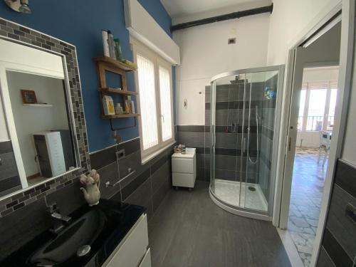 a bathroom with a glass shower and a sink at Sa Caletta Appartamenti in Portoscuso
