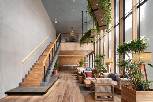 a lobby with stairs and couches and plants at Nest Hotel Naha Kumoji in Naha