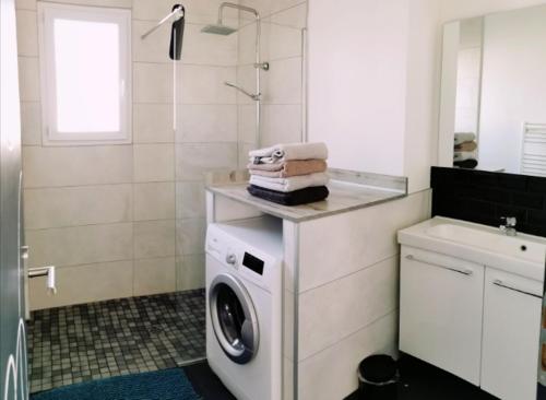 une salle de bain avec une machine à laver et un lavabo dans l'établissement Maison neuve 66m2 Biscarrosse, à Biscarrosse