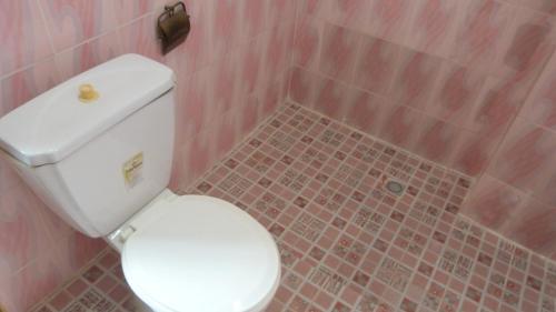 a bathroom with a white toilet and a pink tile floor at Hotel Madou Grand Bassam in Grand-Bassam