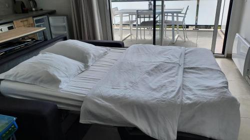 uma cama com lençóis brancos num quarto com varanda em COTE VILLAGE em Nice
