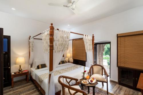 a bedroom with a canopy bed and a table and a chair at WelcomHeritage Badi Kothi in Allahābād