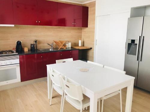 a kitchen with a white table and red cabinets at Casa da Ilha in Madalena