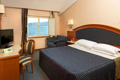 カプラローラにあるHotel La Bella Venereのベッドとテレビが備わるホテルルームです。