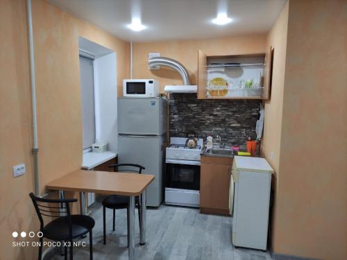 una piccola cucina con tavolo e frigorifero di Квартира студіо біля Автовокзалу a Kremenčuk