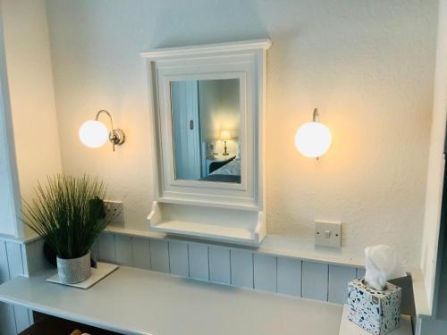 a bathroom with two lights and a mirror at Arden House in Arundel