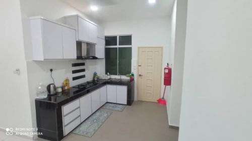 a kitchen with white cabinets and a red fire hydrant at Maryam Homestay in Jertih