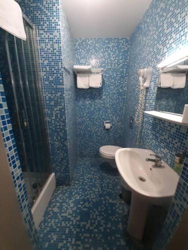 a blue tiled bathroom with a sink and a toilet at hotel Melissa in Péruwelz