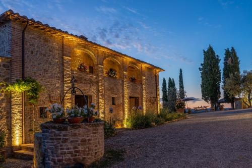 um velho edifício de tijolos com luzes acesas em Agriturismo Poggio Il Castellare em Montalcino