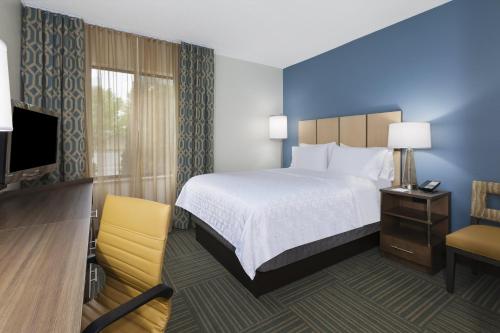 a hotel room with a bed and a television at Candlewood Suites Gonzales - Baton Rouge Area by IHG in Gonzales