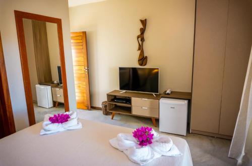 a hotel room with a bed and a television at Villa Zen Hotel in Camocim